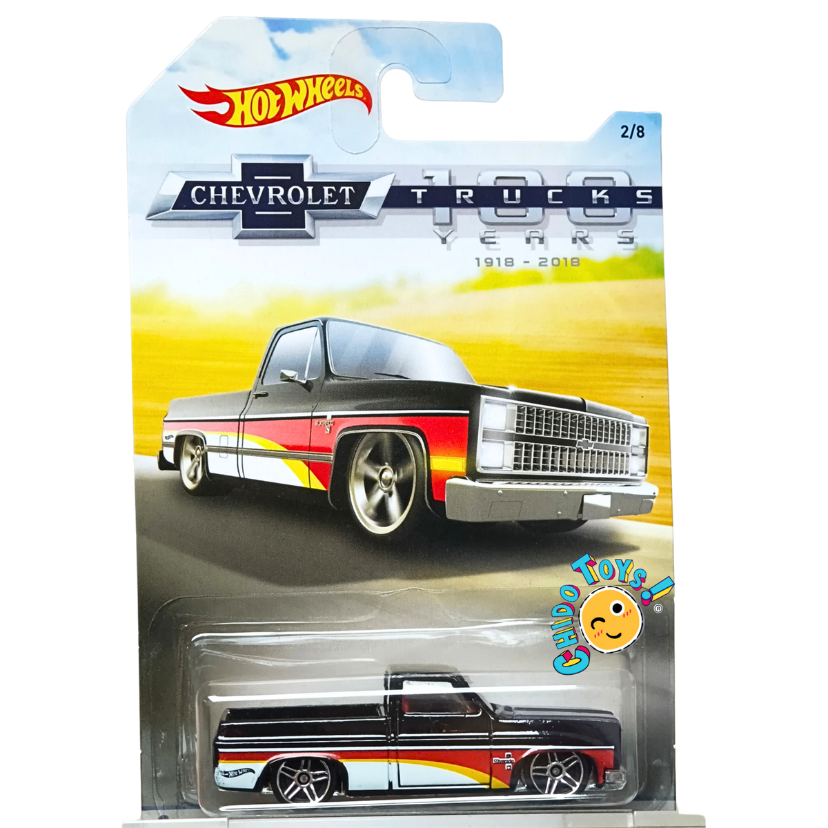 Hot Wheels ’83 Chevy Silverado 1:64 negra, con gráficos rojo, blanco y amarillo, rines de cinco radios y blister original.