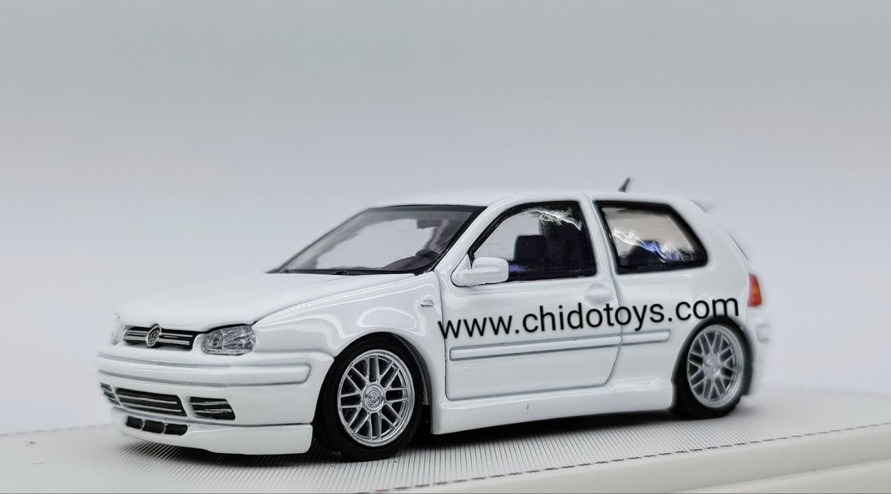 Focal VW Golf GTI Mk4 escala 1:64 blanco con carrocería de metal, cofre abatible, llantas de goma y capelo transparente.