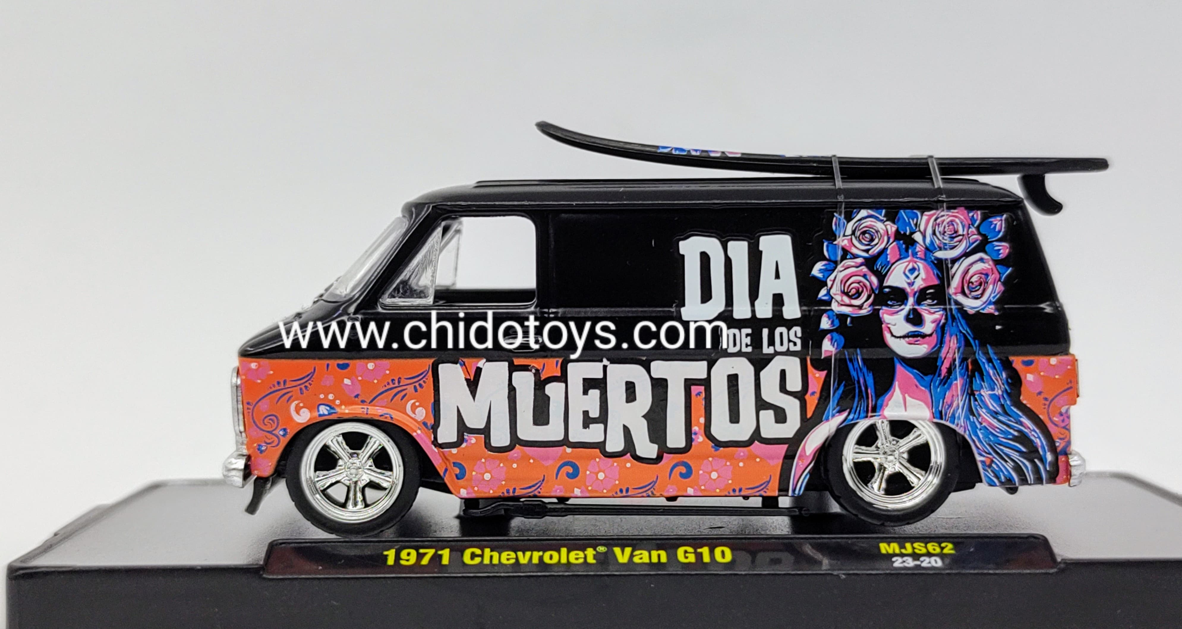 M2 Chevrolet Van G10 1971 1:64 negra y naranja Día de los Muertos con llantas de goma, tabla de surf removible y base con capelo acrílico.