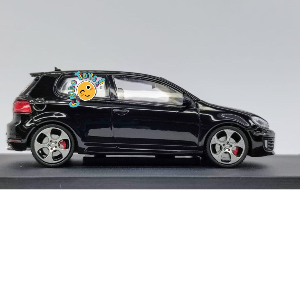 Maxwell Volkswagen Golf GTI Mk6 1:64 negro con llantas de goma, apertura de cofre, motor detallado, base y capelo.