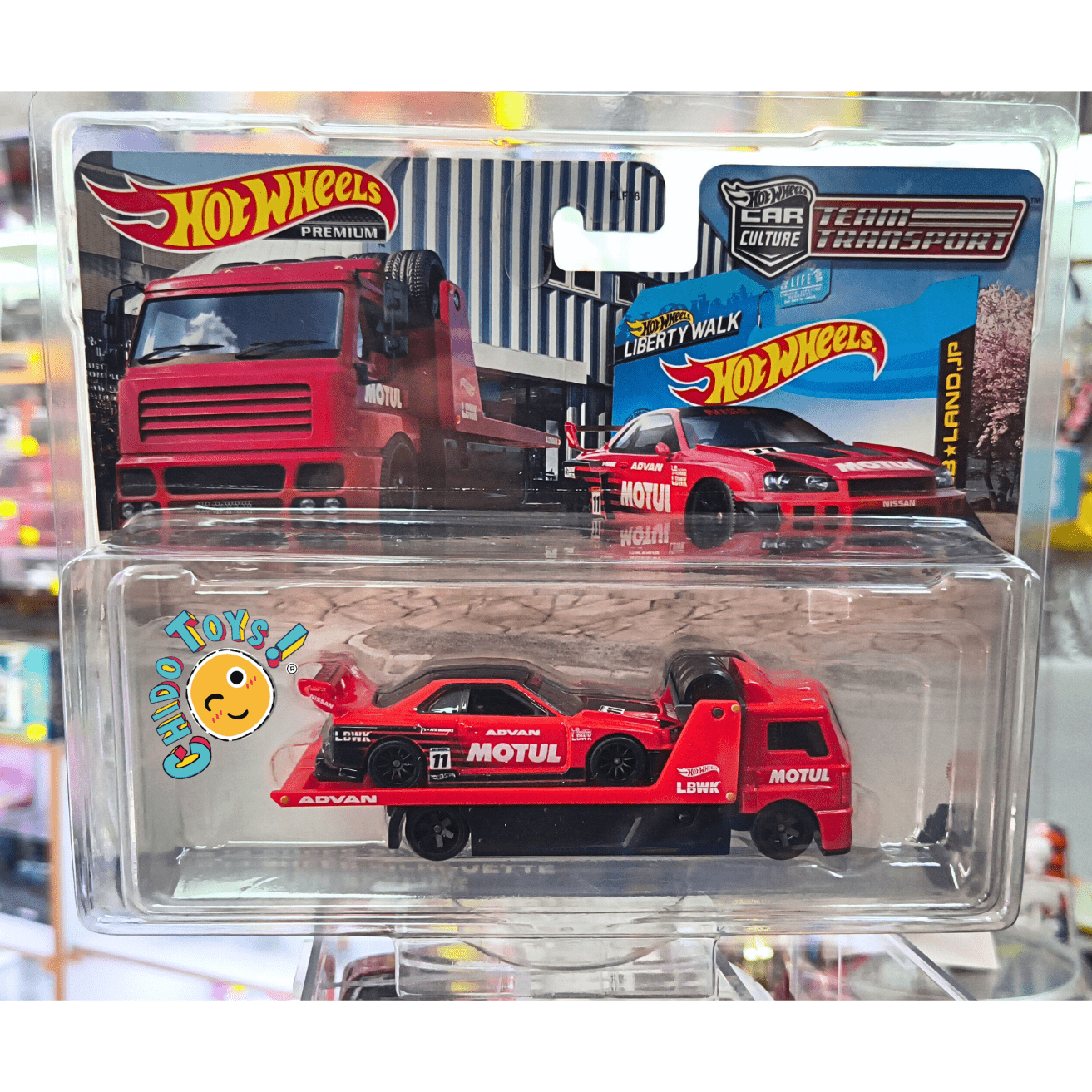 Hot Wheels Premium Team Transport – LBWK Nissan Skyline GT - R (R34) + Aero Lift 1:64 – Metal/Metal, Real Riders – Con protector - Chido Toys