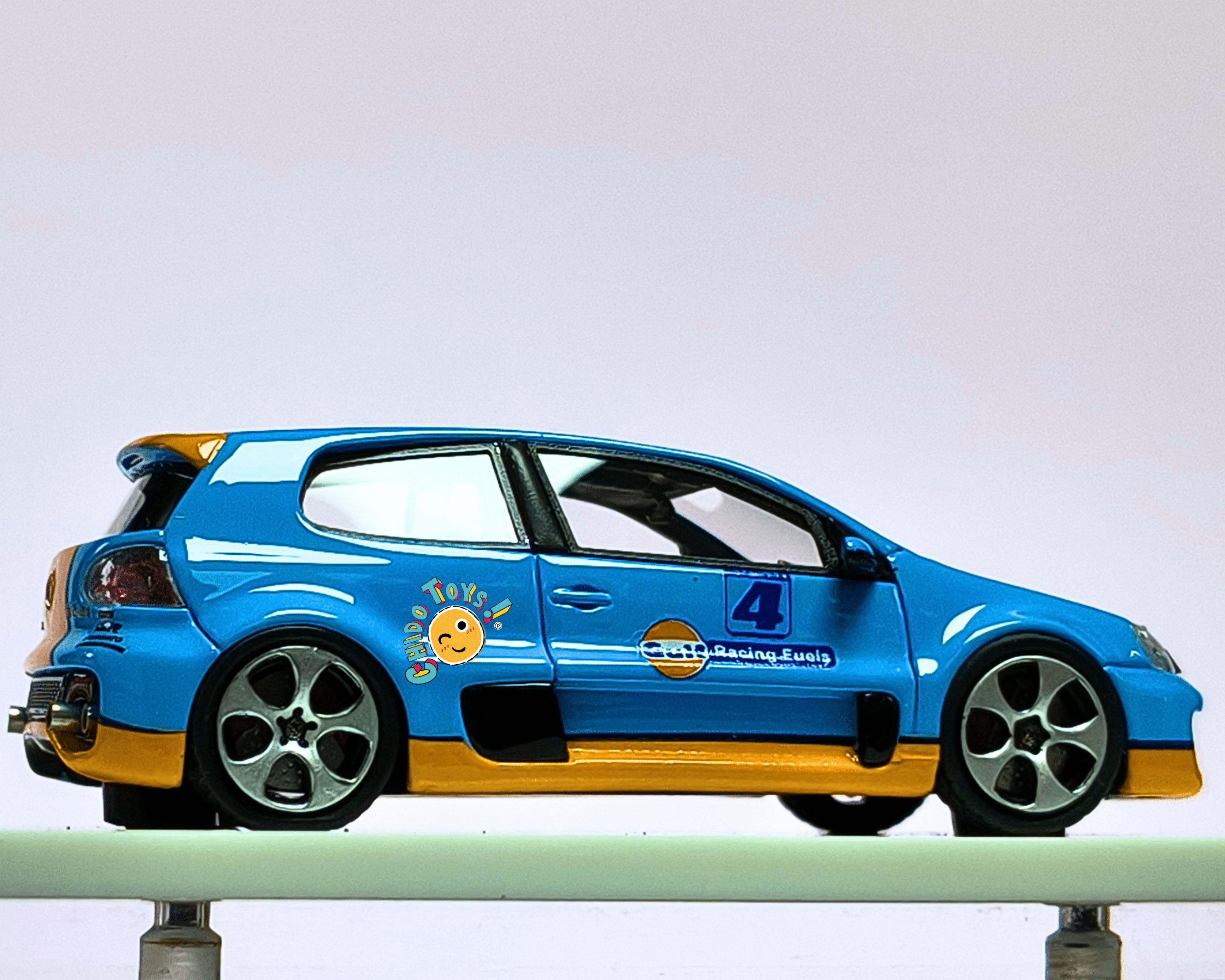 Volkswagen Golf GTI Gulf Racing 1:64 con Capelo Acrílico y Llantas de Goma - Chido Toys